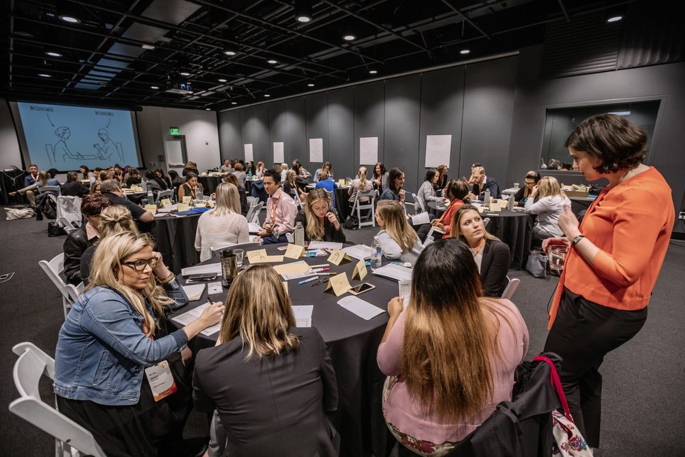 Attendees working together at round tables in a workshop
